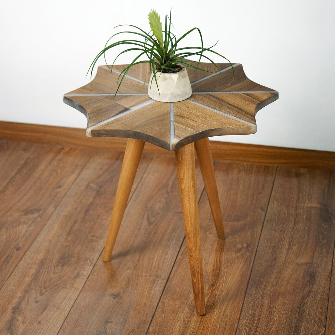 Close-up of the walnut snowflake side table top with white epoxy stripes and tripod legs